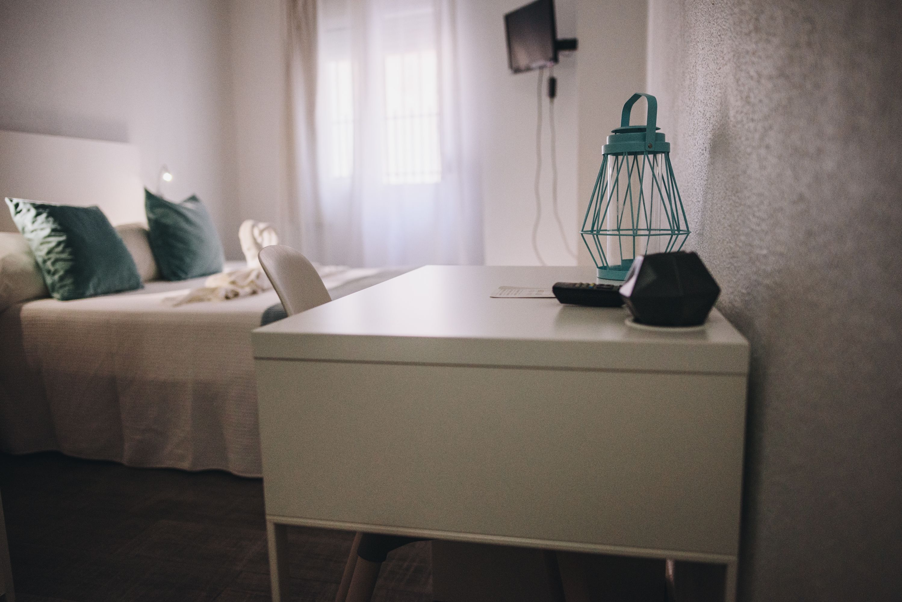 Een netjes opgemaakt slaapkamer met een bed, nachtkastje en lamp.