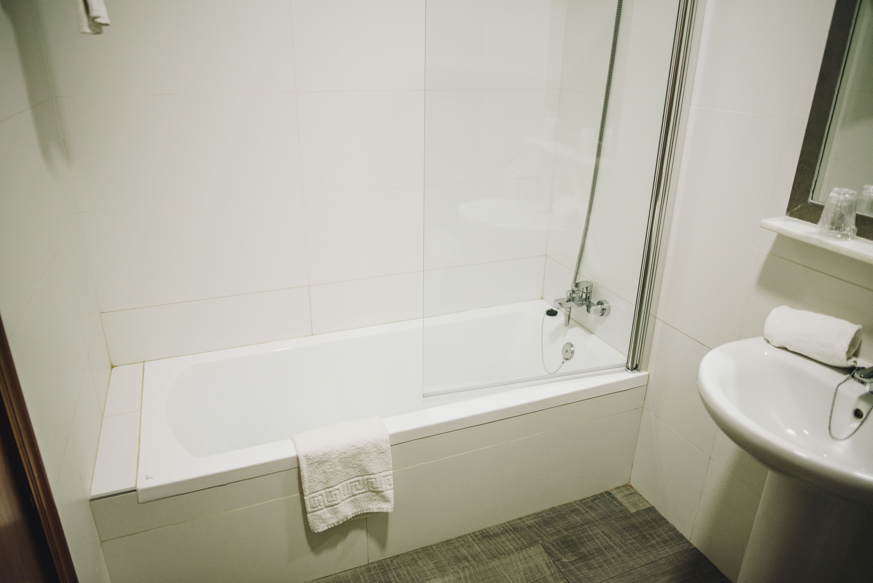 A bathroom with a white bathtub, a sink, and a mirror.
