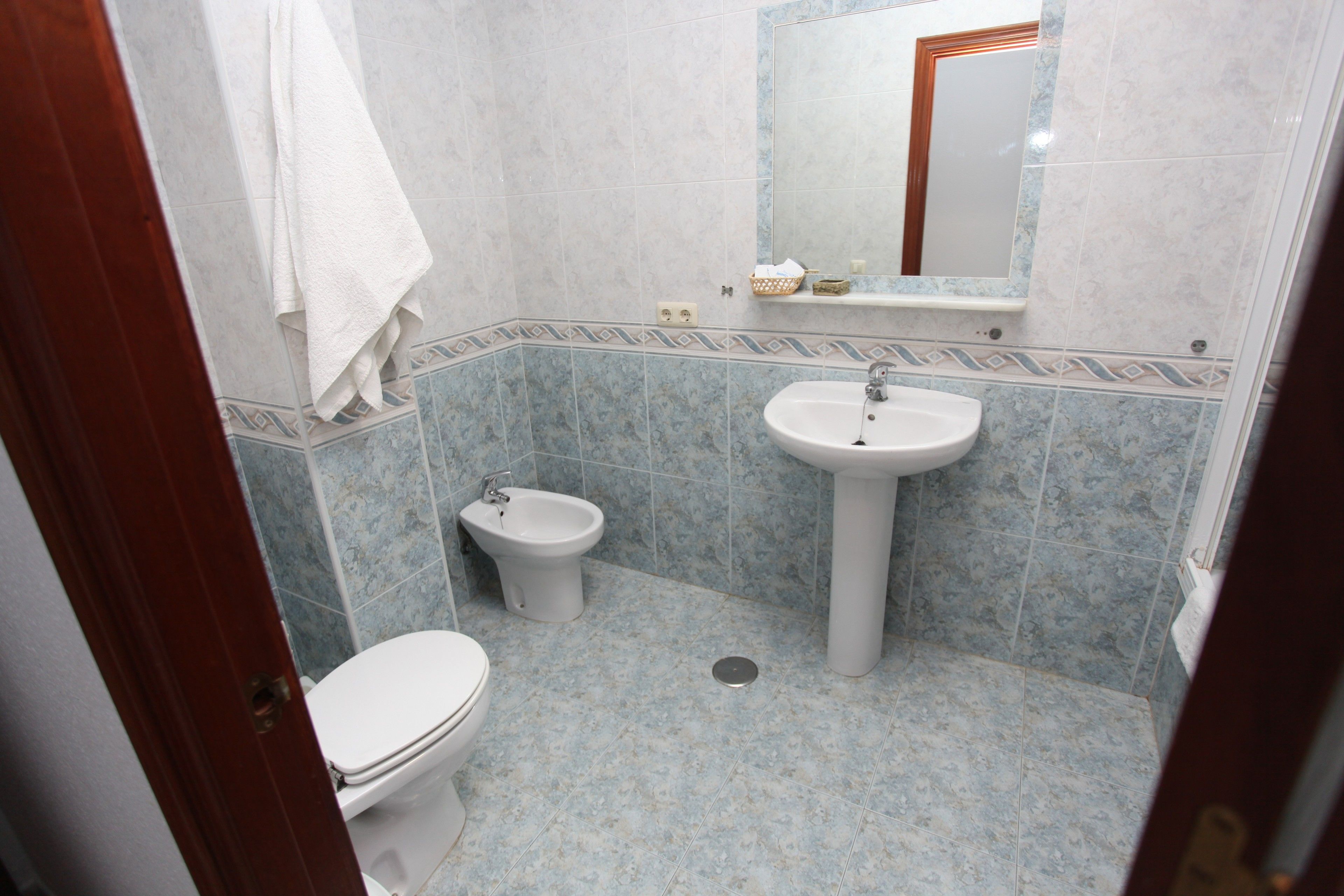 A bathroom with a toilet, bidet, sink, and mirror.