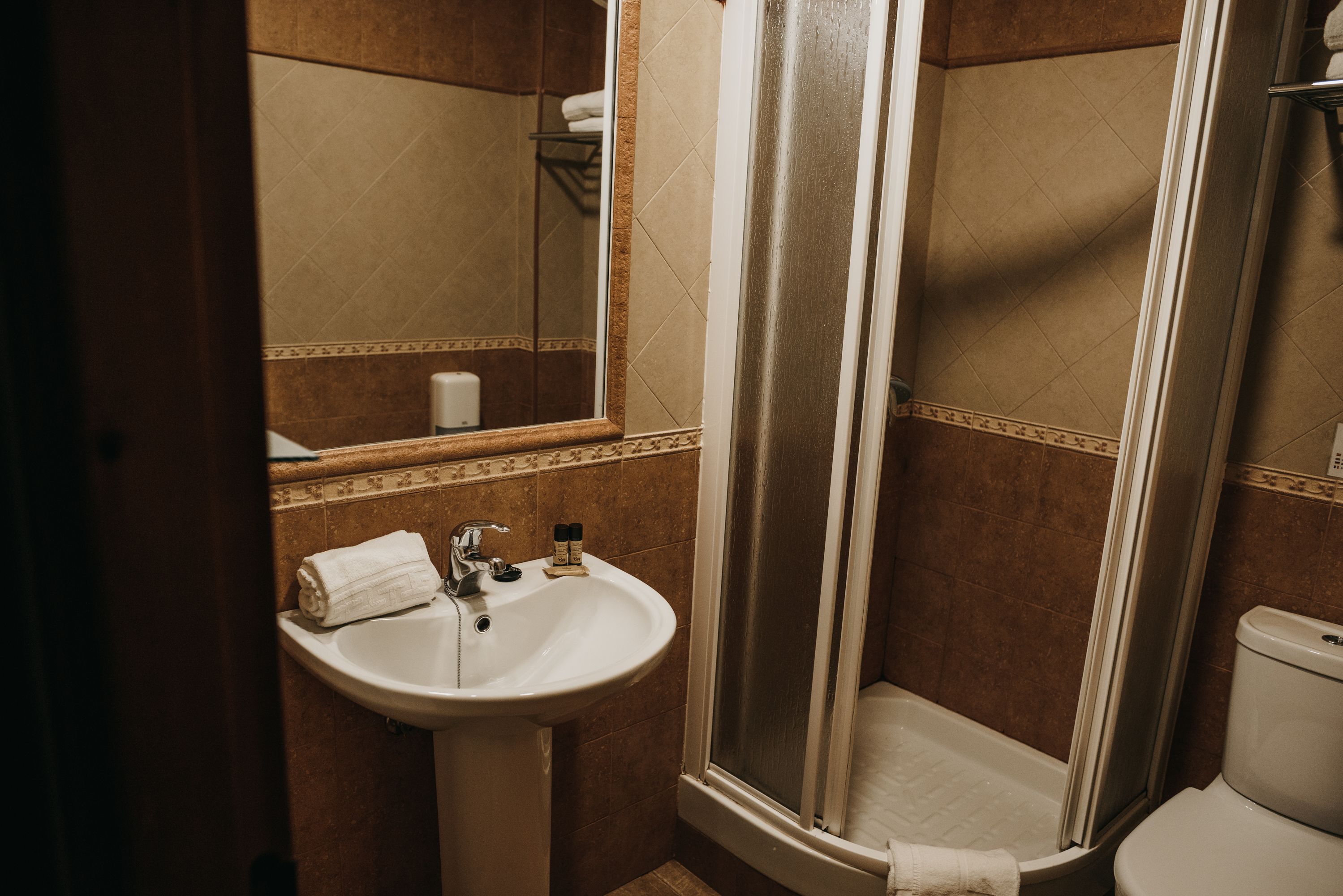 A bathroom with a sink, mirror, and shower.