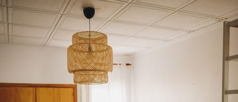 Un dormitorio con cama, armario, escritorio y lámpara colgante.