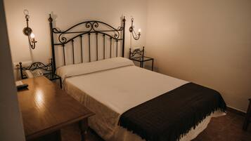 Una cama bien hecha con cabecera, mesitas de noche y lámparas de pared.