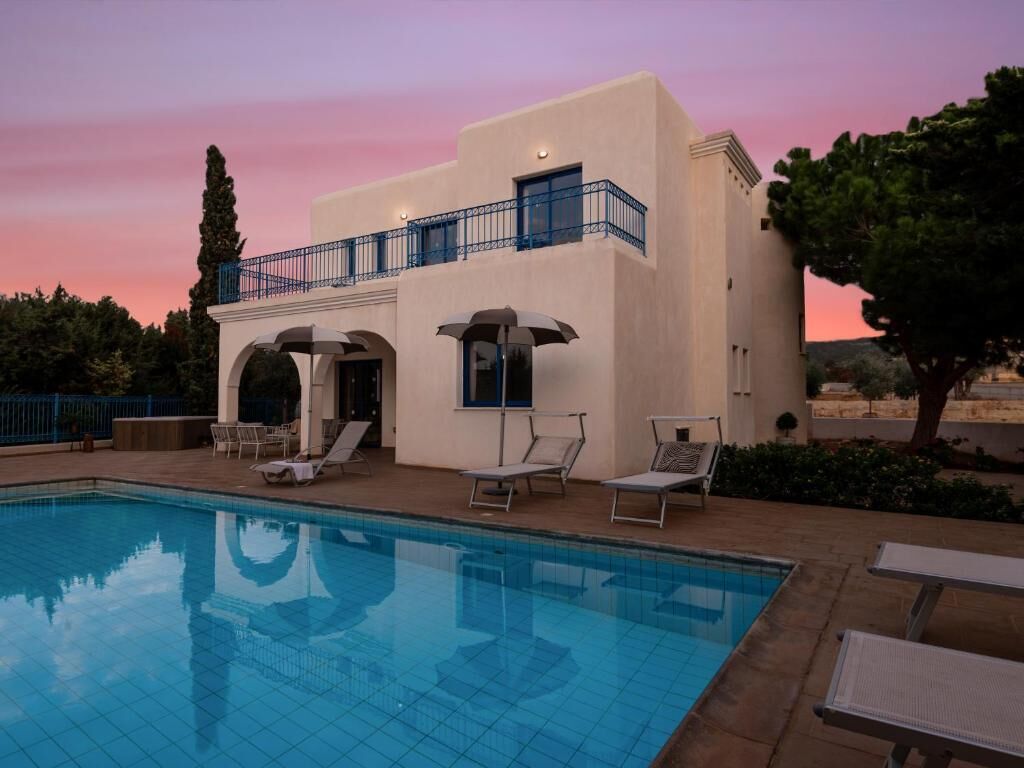 Un espace aménagé au bord de la piscine, comprenant une piscine, des chaises longues et un bâtiment doté d’un balcon.