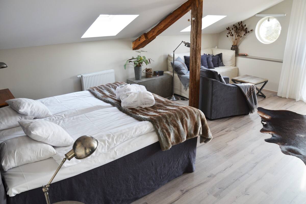 A bedroom with a bed, bedside lamp, and a window with a view of the outdoors.