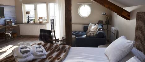 Una habitación acogedora con una cama, una silla, una mesa y una ventana.