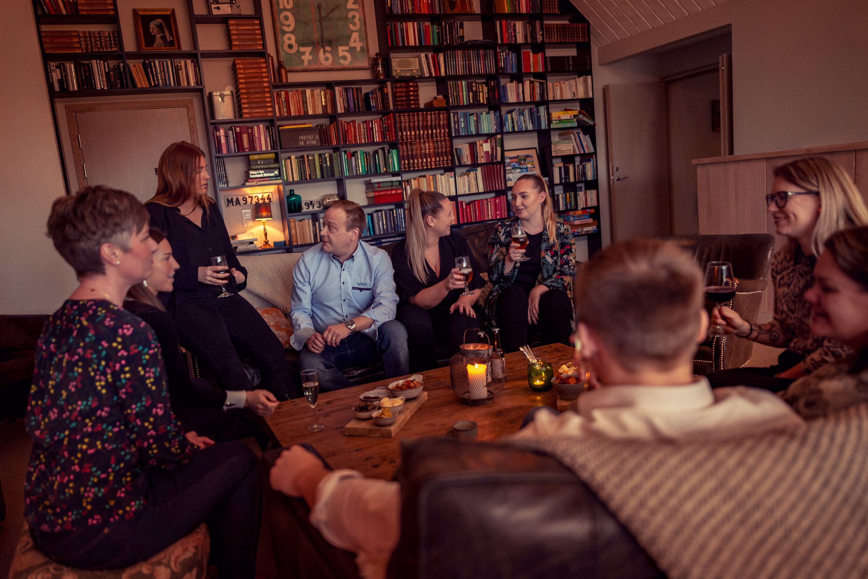A group of people sitting around a wooden table in a room with bookshelves filled with books.