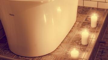 Une baignoire dotée d’un robinet et d’une pomme de douche, entourée de carreaux décorés.