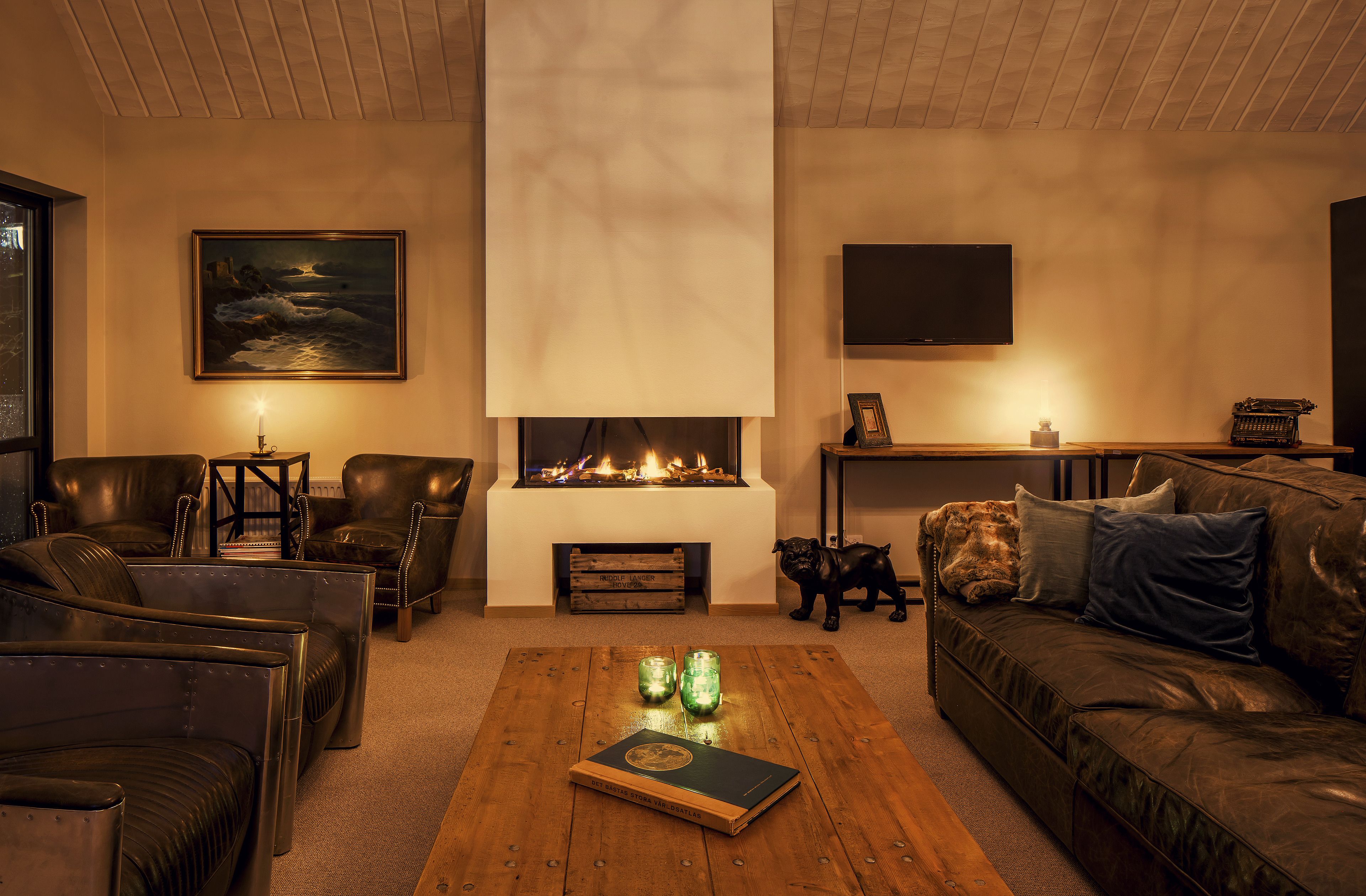 A cozy living room with leather furniture, a fireplace, and a painting on the wall.