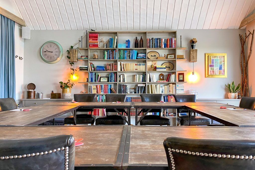 A library with bookshelves, a clock, and a table with chairs.