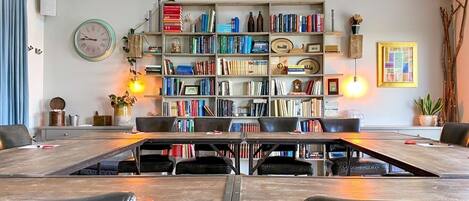 A library with bookshelves, a clock, and a table with chairs.