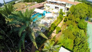 A hotel with a swimming pool, outdoor seating, and lush greenery. - Fitos Inn Guest House (Geroskipou)