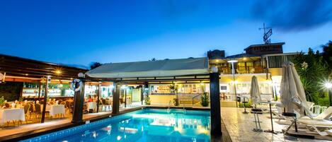 Een buitenzwembad, parasols bij het zwembad en ligstoelen