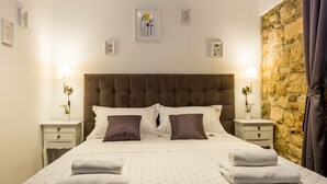 A neatly made bed with two pillows, a headboard, and two bedside tables with lamps. - XIV Century rooms (Kastela)