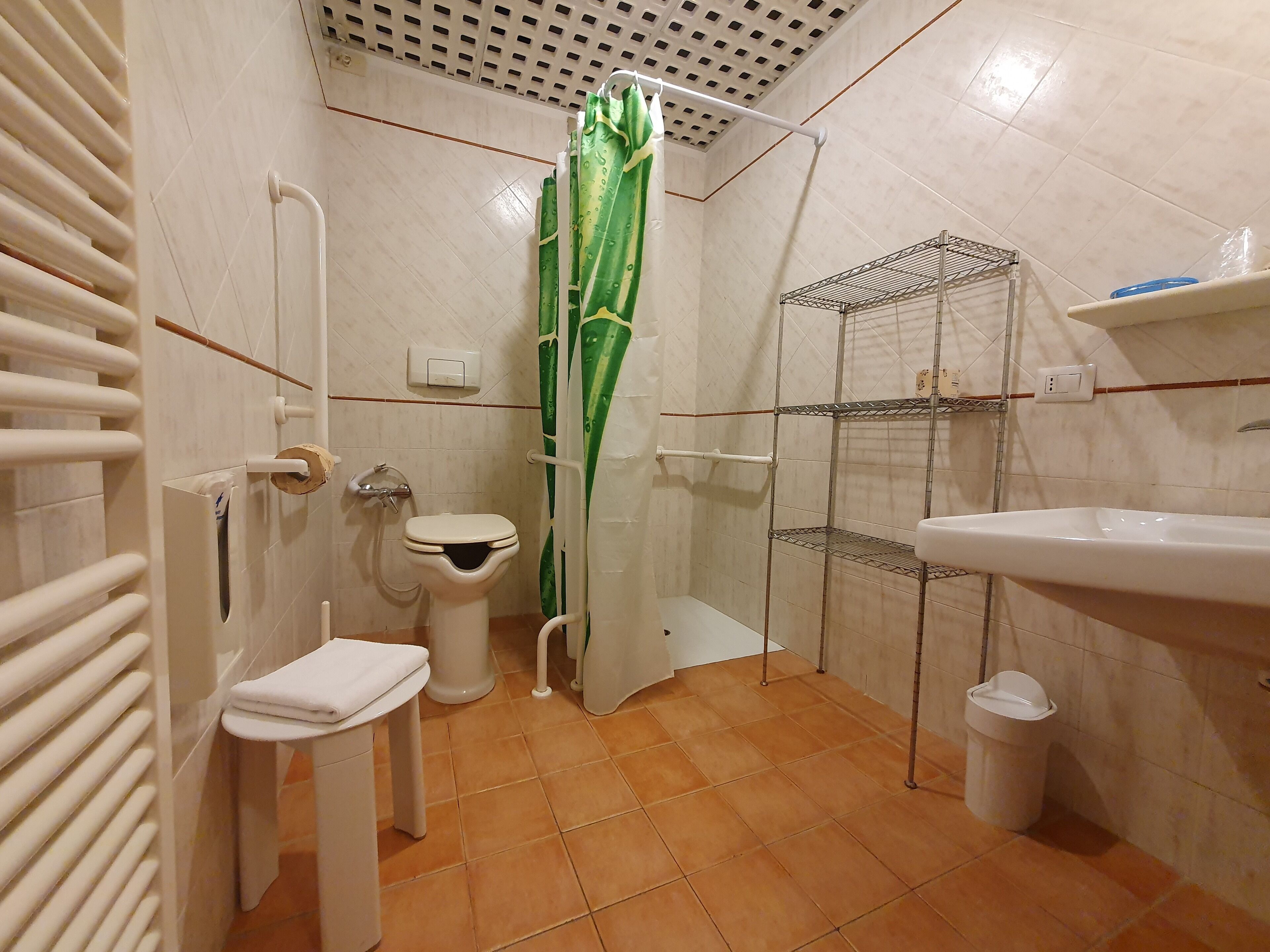 Un baño con inodoro, ducha, lavamanos y estanterías.