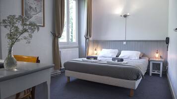 Un dormitorio con cama, mesitas de noche, escritorio y ventana con cortinas.