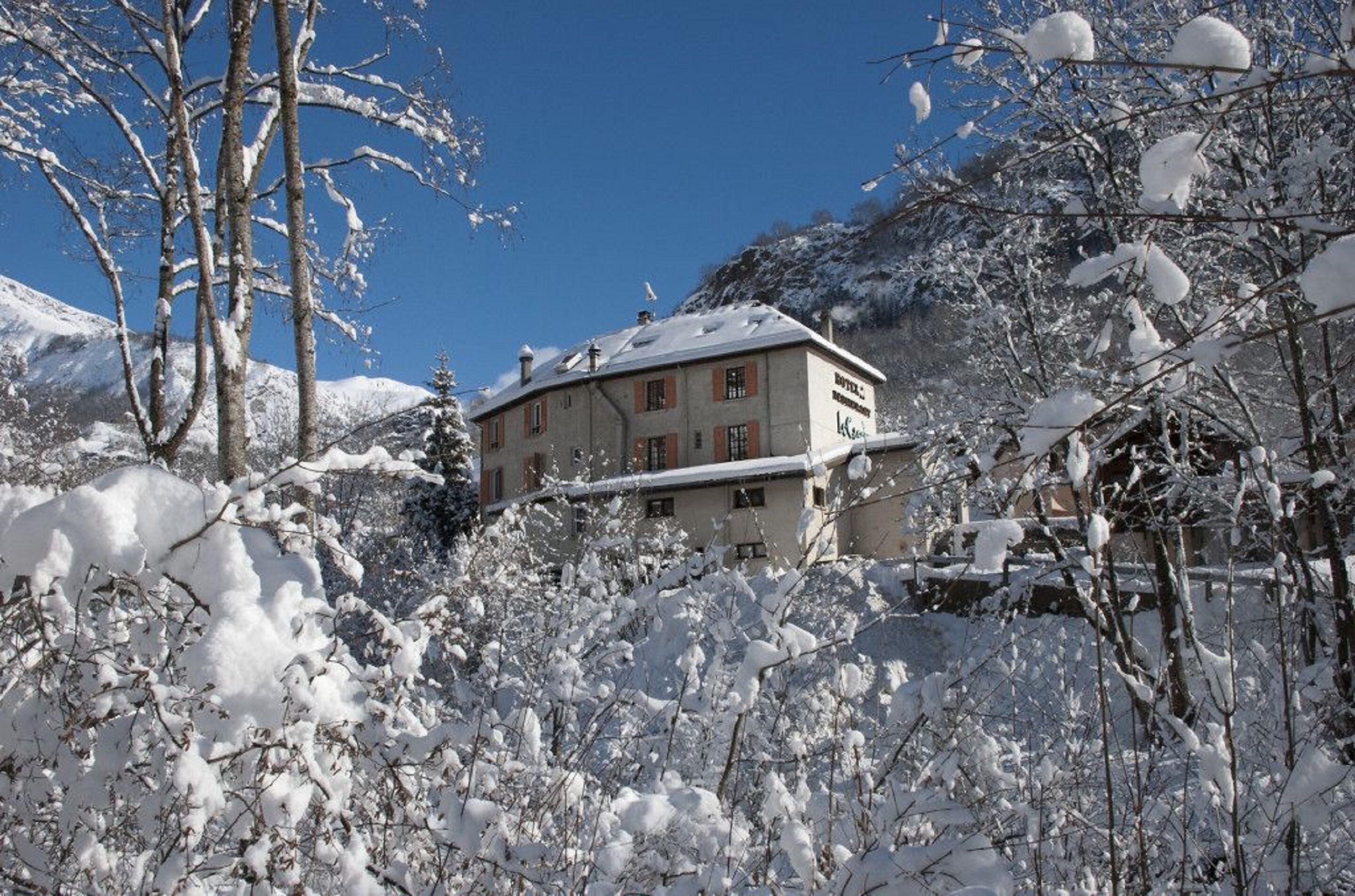 Een gebouw omringd door sneeuwbedekte bomen en bergen.