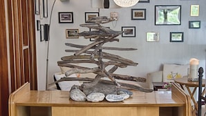 A wooden cabinet with a decorative tree sculpture on top, surrounded by framed pictures on the wall.