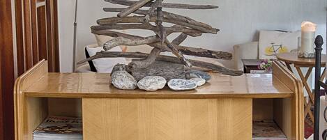 Um armário de madeira com uma escultura decorativa de árvore no topo, rodeado por quadros nas paredes.