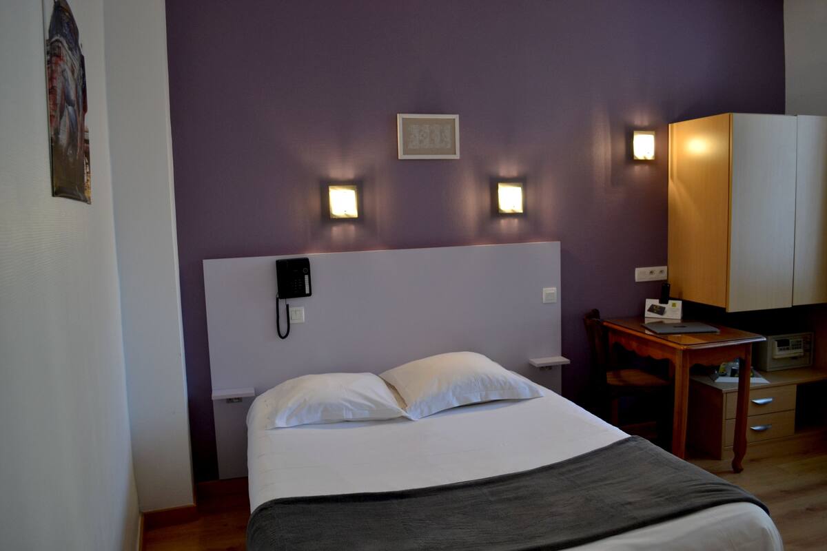 Ett hotellrum med en säng, ett sängbord, en lampa och en garderob.