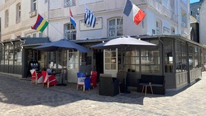 A restaurant with outdoor seating, a signboard, and flags. - Hotel De La Porte Saint Pierre (Saint-Malo)