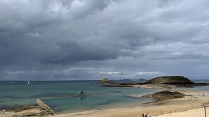 A coastal landscape with a rocky beach, clear water, and a cloudy sky. - Hotel De La Porte Saint Pierre (Saint-Malo)
