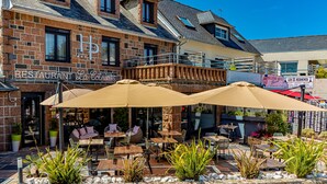 A restaurant with outdoor seating, stone walls, and potted plants. - Hotel Du Parc (Perros-Guirec)