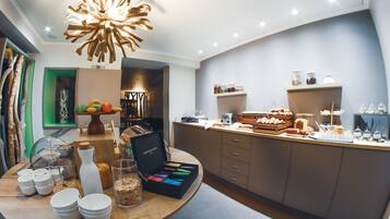 A modern kitchen with a central island, a variety of food items, and a unique chandelier.