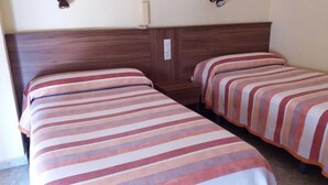Ein Zimmer mit zwei Betten, jeweils mit gestreifter Bettwäsche.