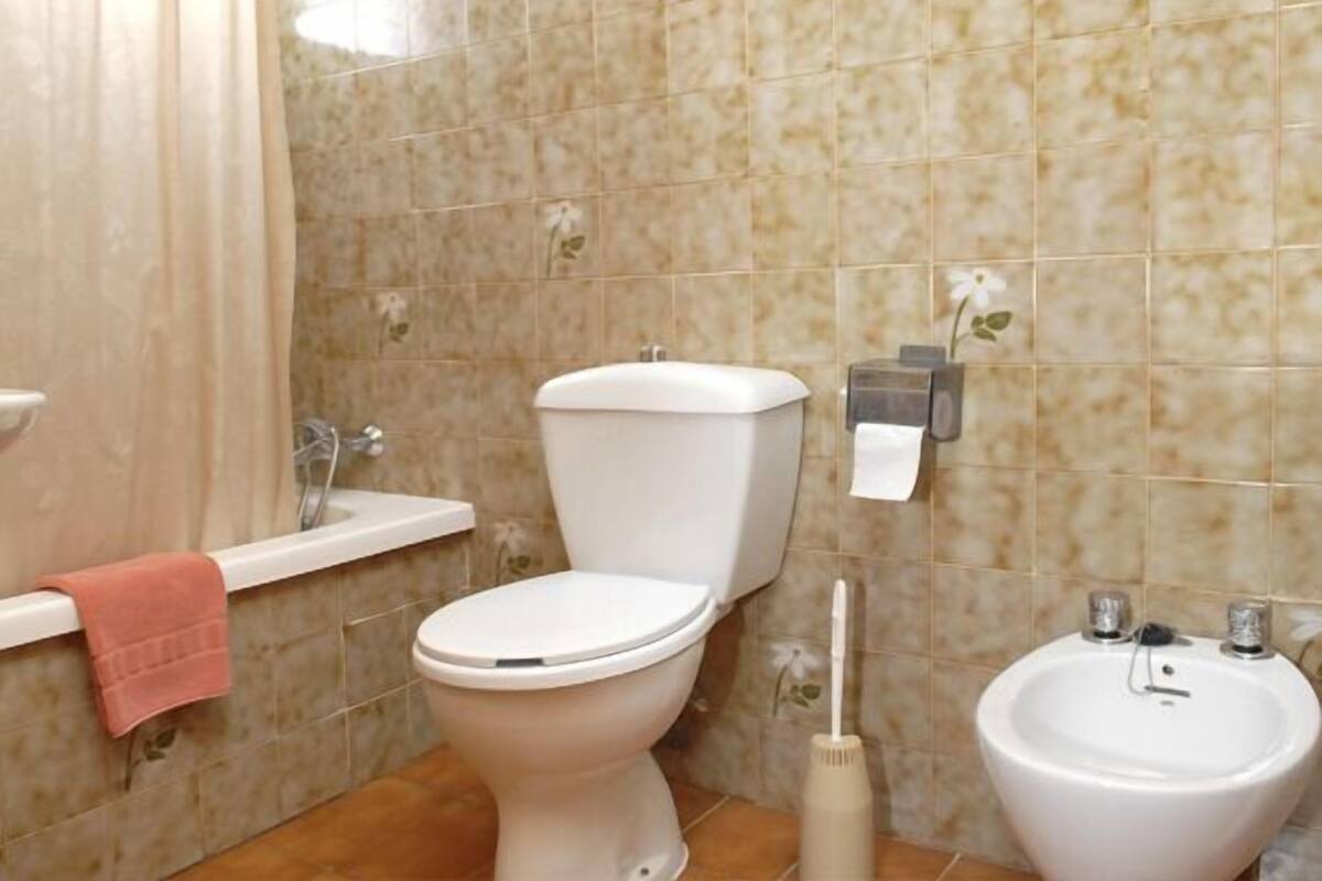 Une salle de bain équipée de toilettes, d’un lavabo, d’un bidet et d’un porte-serviettes.