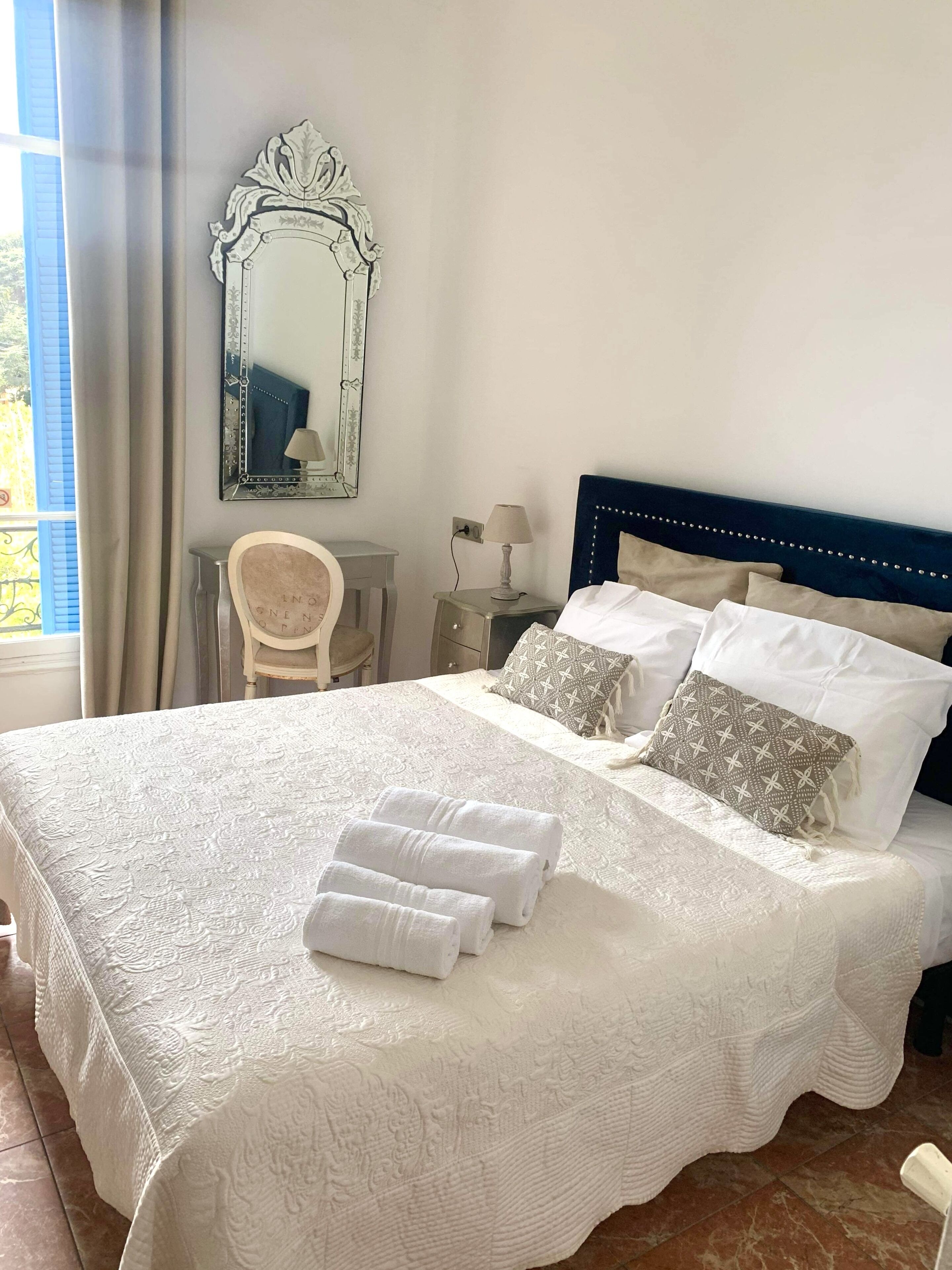 A neatly made bed with white linens, a headboard, and decorative pillows.