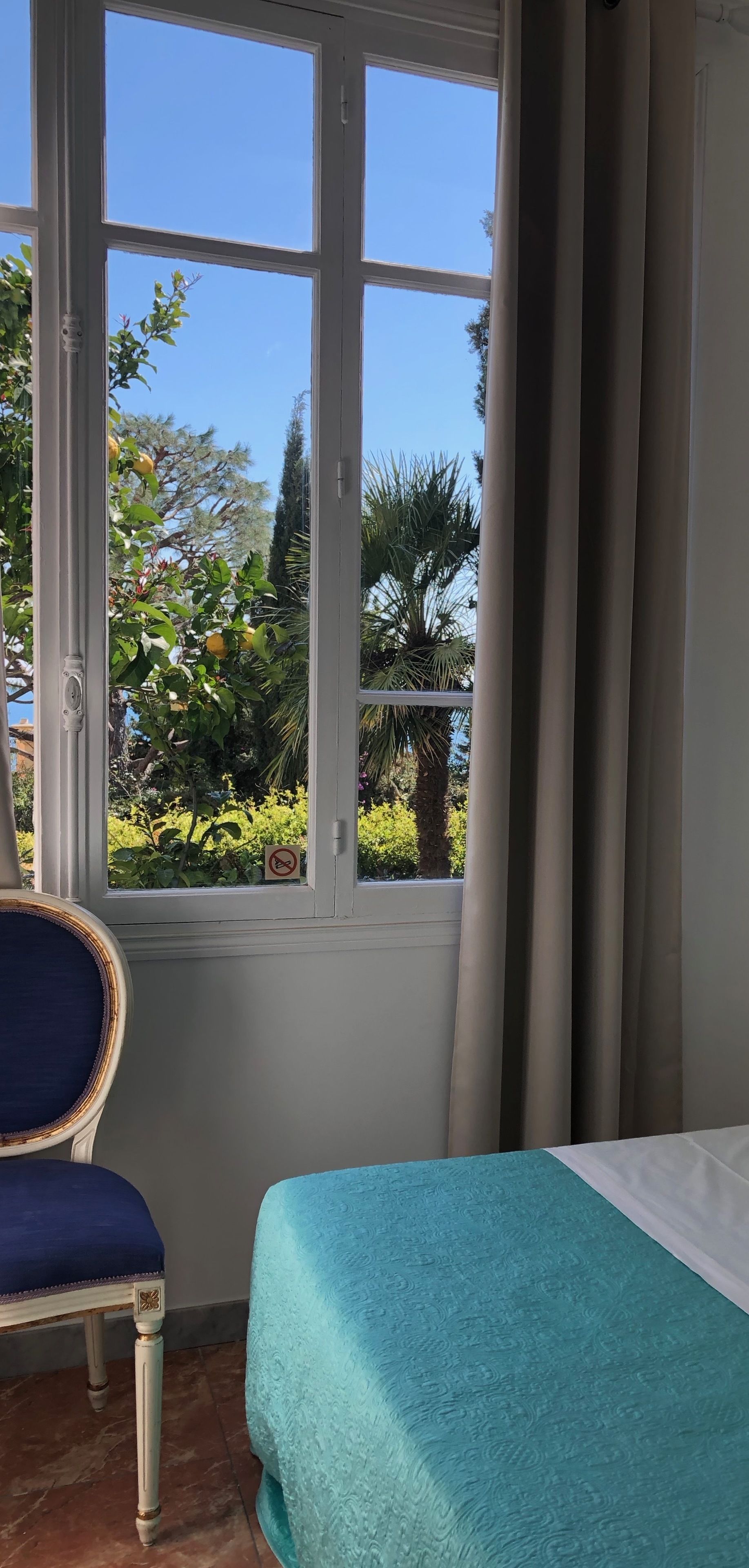 A room with a bed, a chair, and a window with curtains.