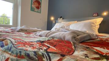 Een hotelkamer met een bed, een raam en een wandlamp.