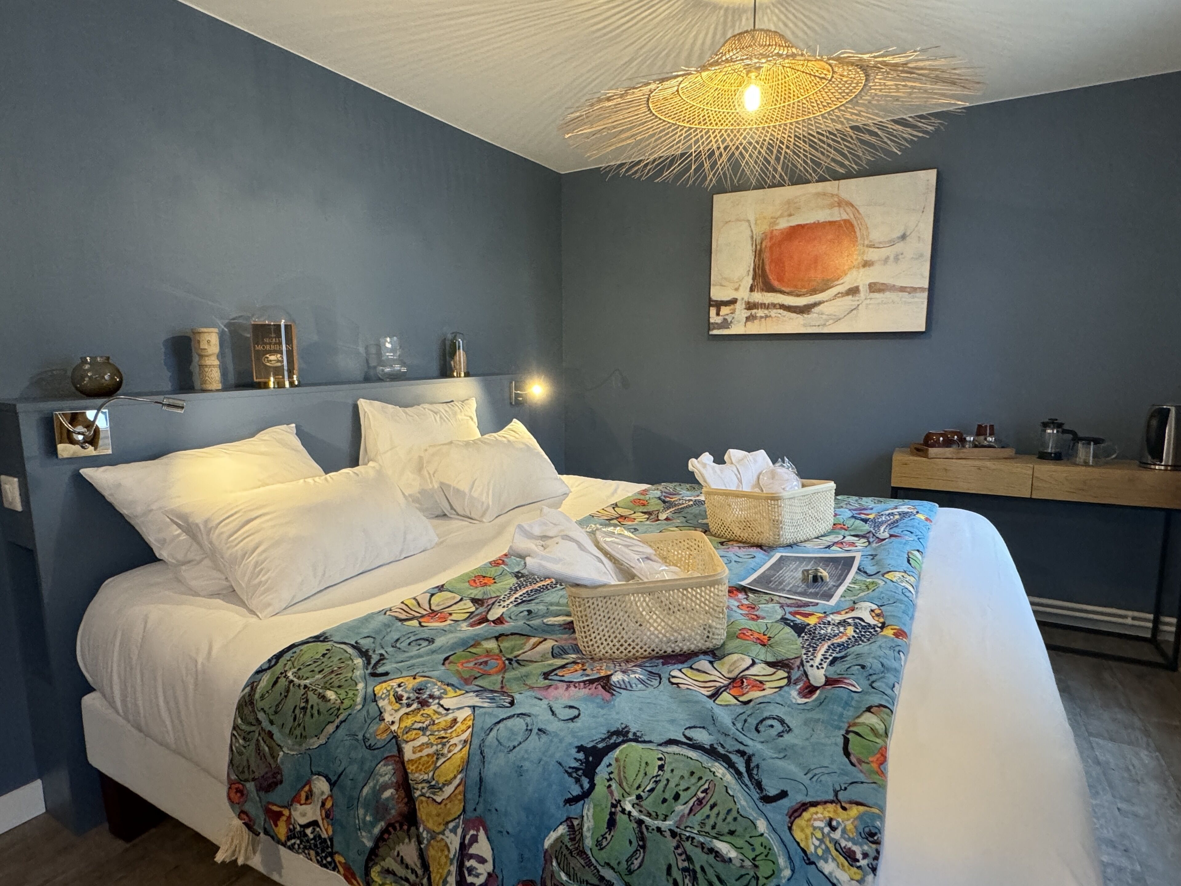 A bedroom with a bed, a bedside table, a lamp, a wall art piece, and a ceiling light fixture.
