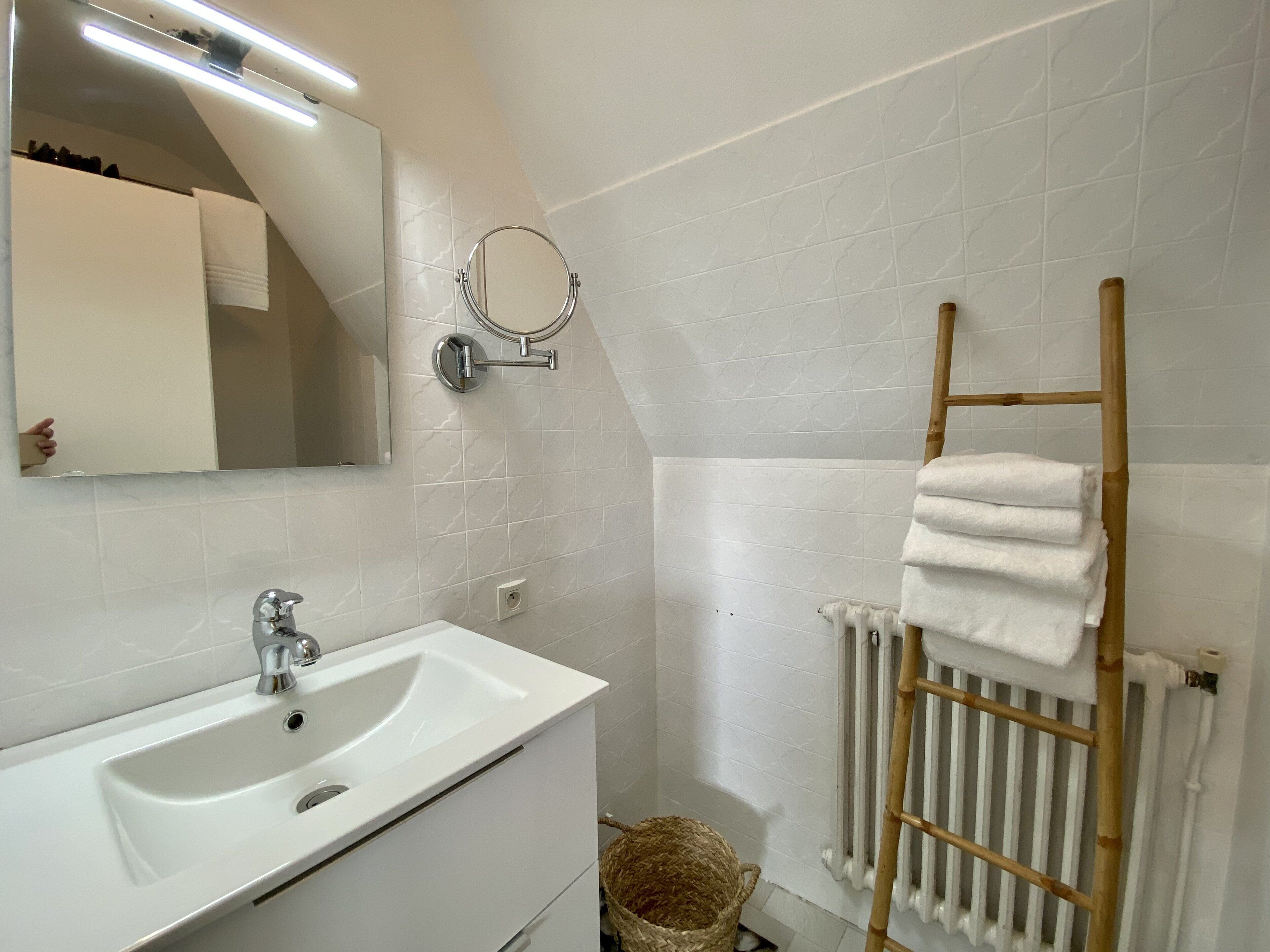 Un baño moderno con un lavamanos, un espejo y un perchero para toallas.
