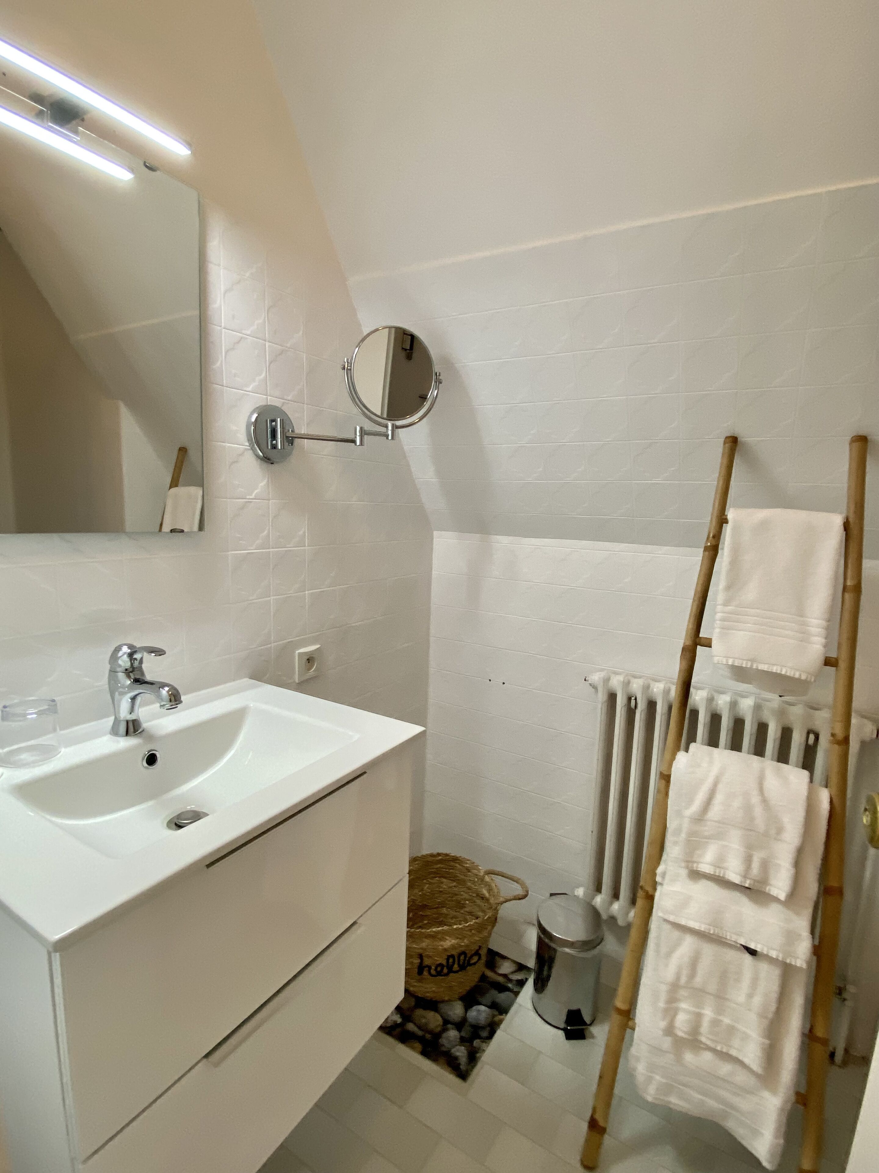 Une salle de bain avec un lavabo blanc, un miroir et un porte-serviettes.