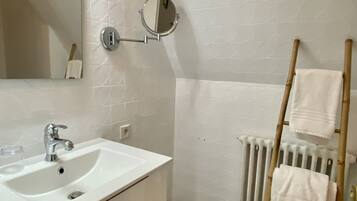 Une salle de bain avec un lavabo blanc, un miroir et un porte-serviettes.