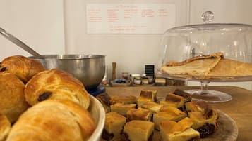 A buffet with various baked goods including croissants, a bowl of soup, and a covered dish of pie.