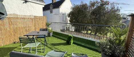 A patio with a table and chairs, a small lawn, and a wooden fence.