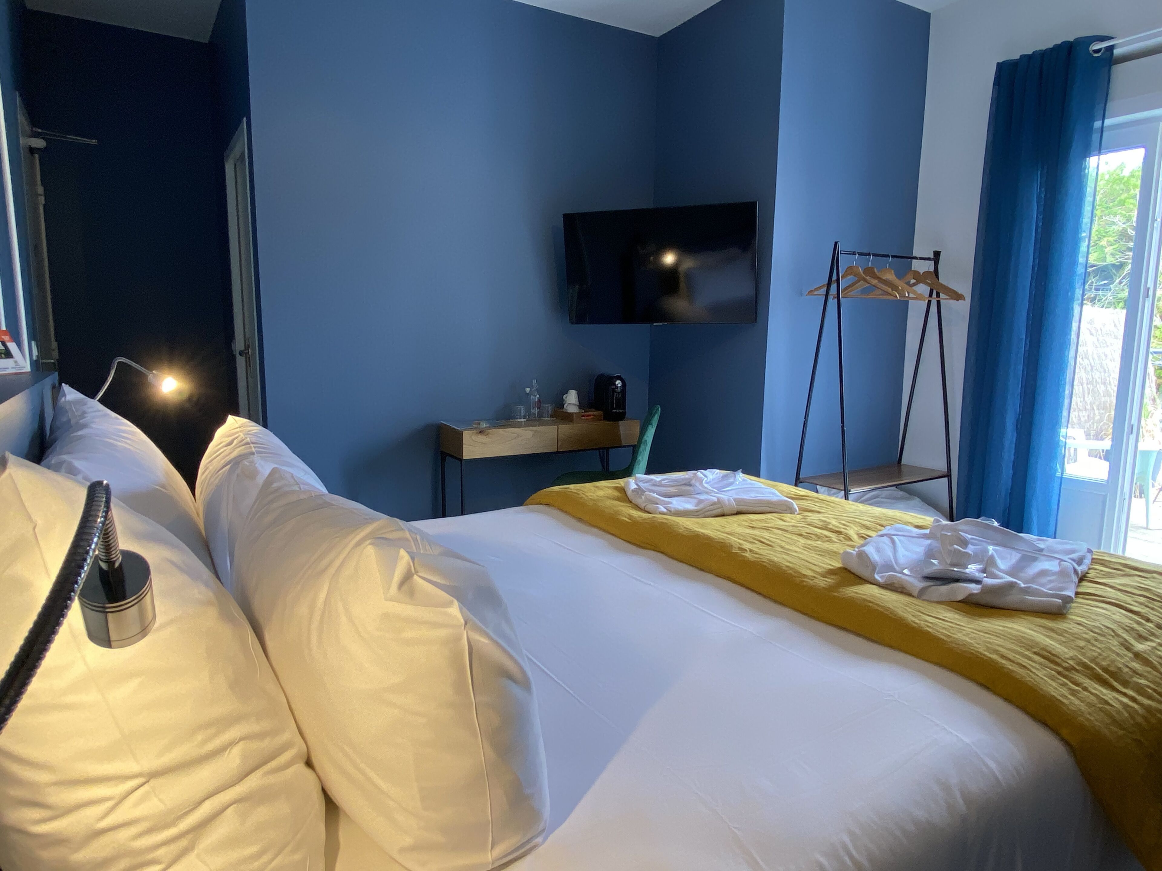 Une chambre d’hôtel avec un grand lit, un bureau doté d’un téléviseur à écran plat, une chaise et une fenêtre avec des rideaux.