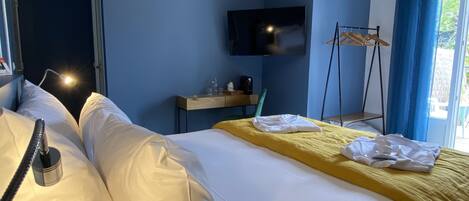 Une chambre d’hôtel avec un grand lit, un bureau doté d’un téléviseur à écran plat, une chaise et une fenêtre avec des rideaux.