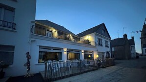 Un immeuble de deux étages doté d’un balcon, de grandes fenêtres et d’une clôture à l’avant.
