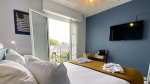 Une chambre d’hôtel avec un grand lit, un bureau en bois, un téléviseur à écran plat et une vue sur l’extérieur.