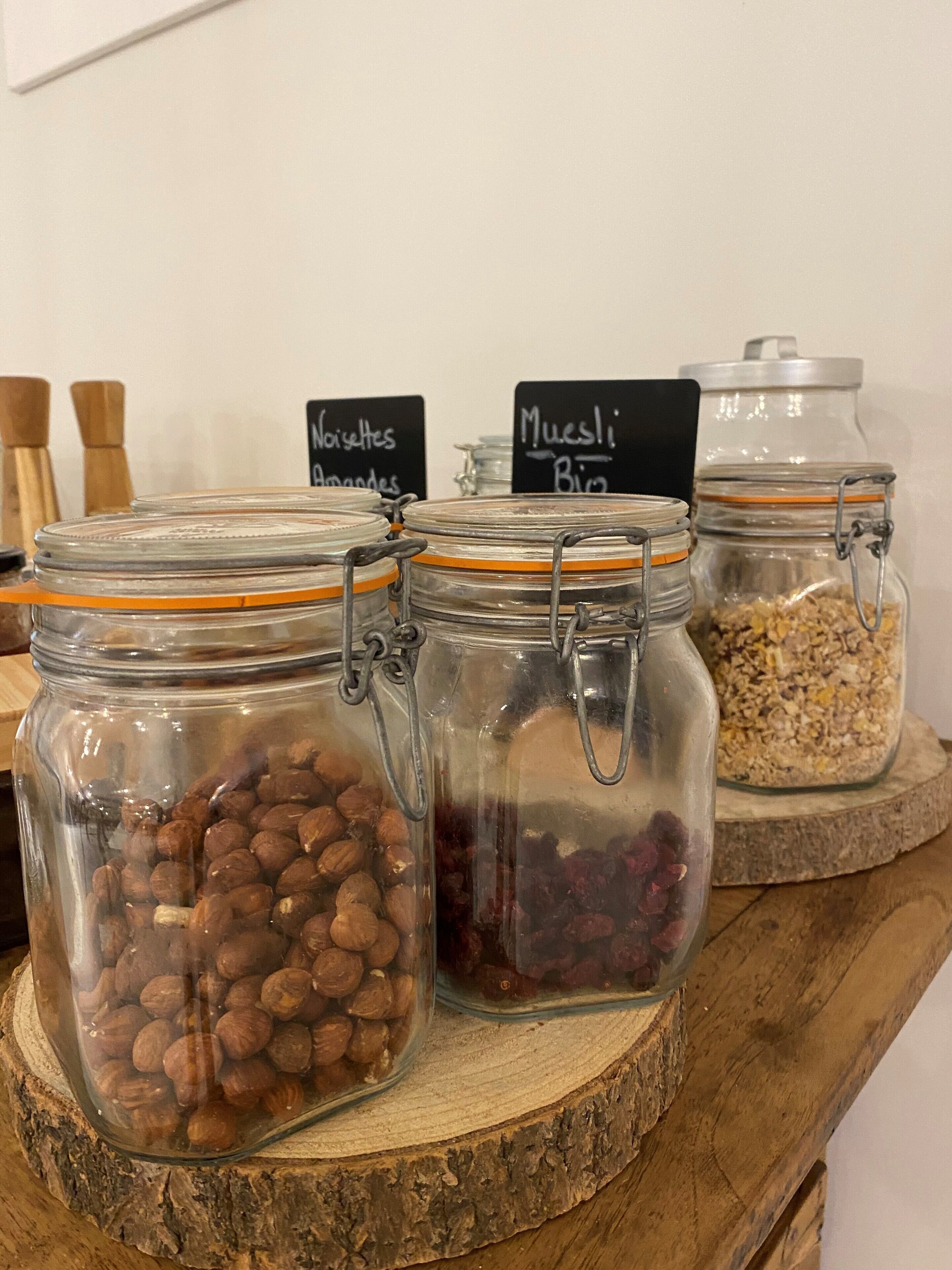 Three glass jars with metal clasps on a wooden surface, each labeled with handwritten signs indicating different contents.
