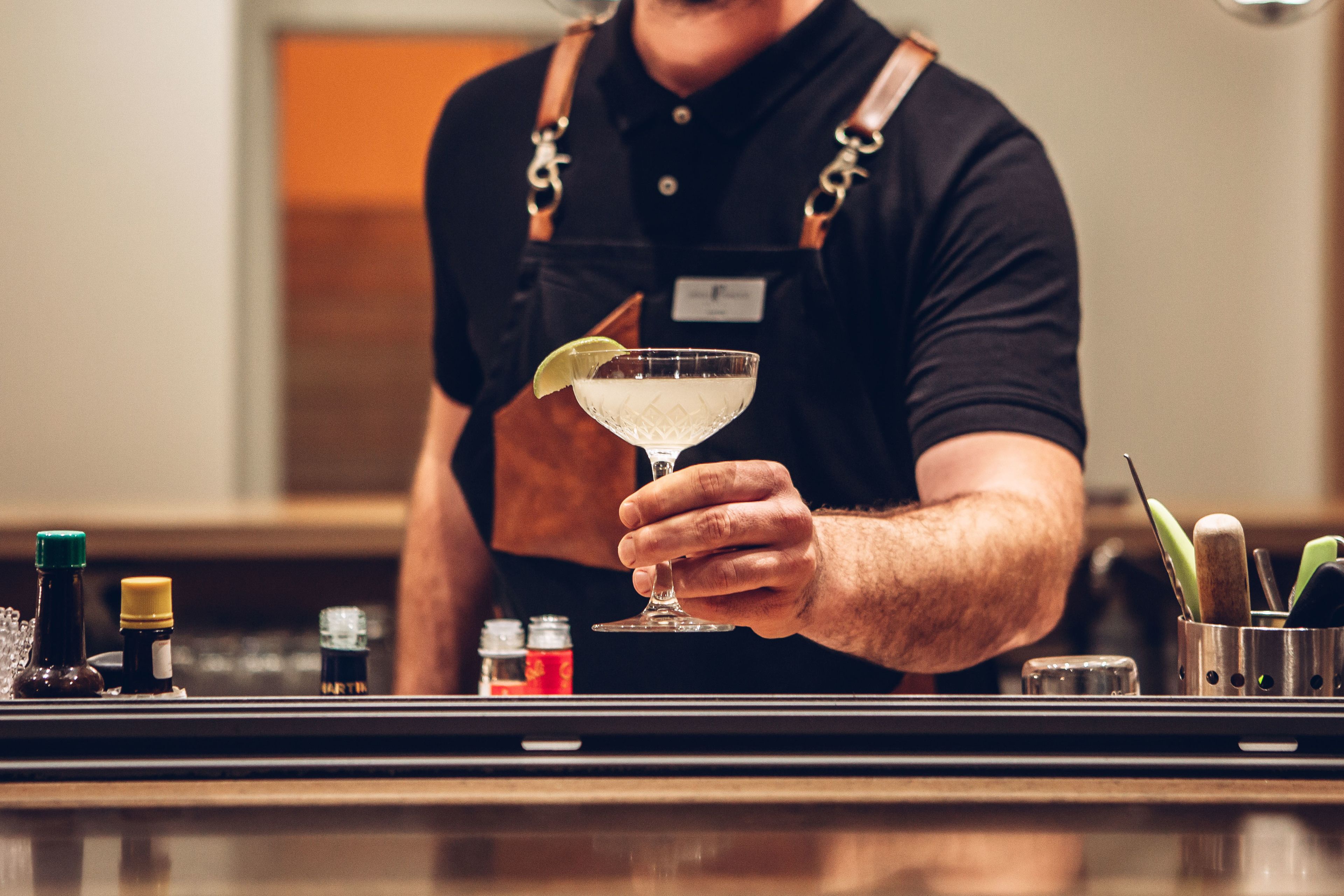 Ein Barkeeper hält ein Cocktailglas mit Limettenscheibe.