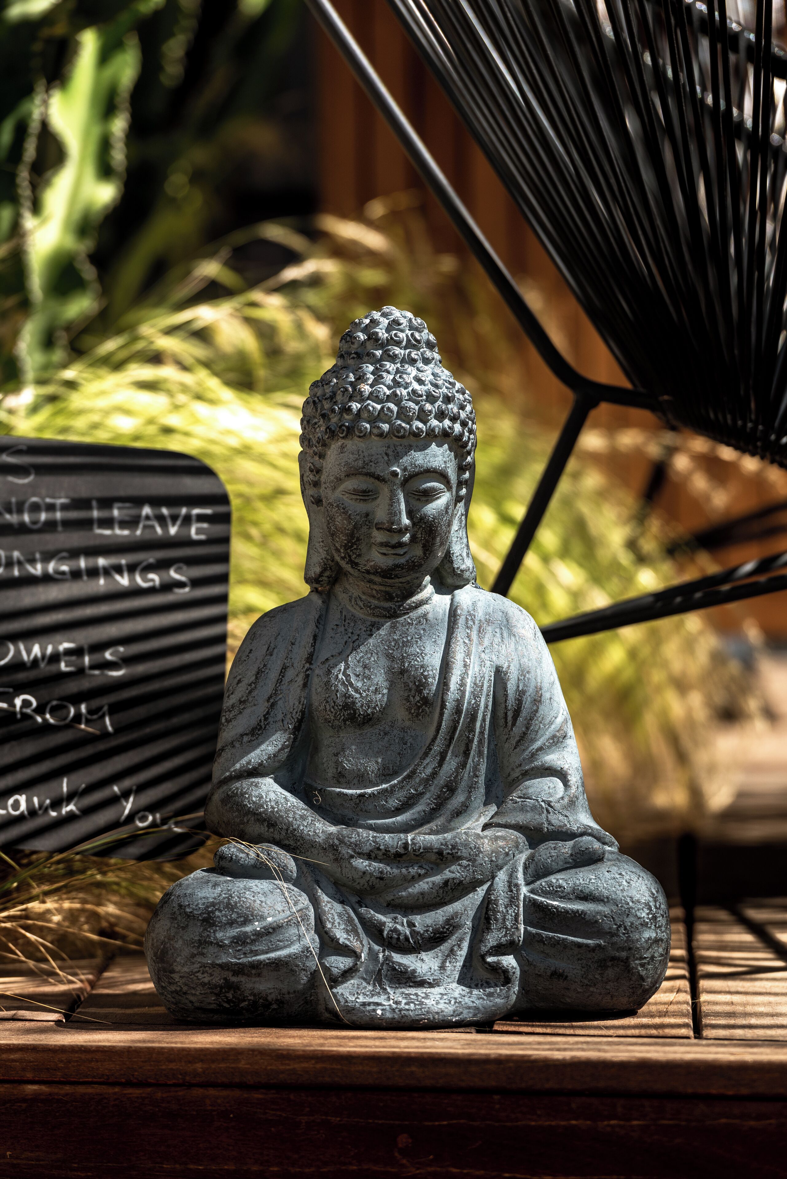 A stone Buddha statue on a wooden platform with a sign in the background.