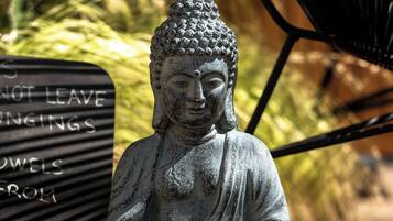 A stone Buddha statue on a wooden platform with a sign in the background.