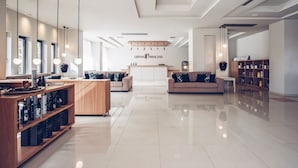 Un vestíbulo amplio con mostrador de recepción, sofás, una estantería de madera e iluminación colgante.