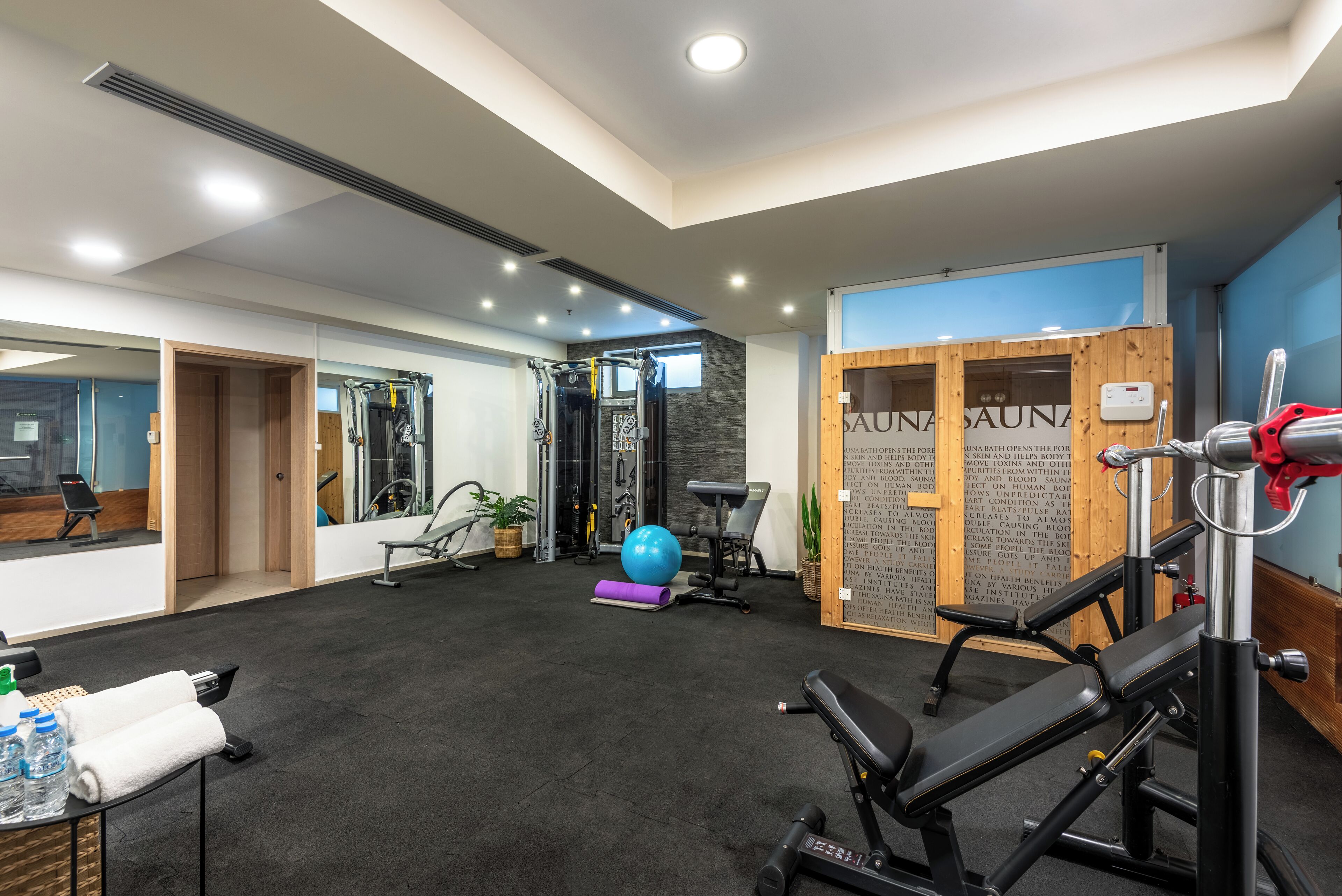Een fitnessruimte met trainingsapparatuur, een massagestoel en een sauna.