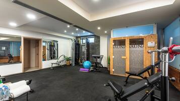 Et fitnesscenter med træningsudstyr, en massage-stol og en sauna.