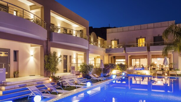 Un hotel de varios pisos con piscina, zona de estar al aire libre y una entrada bien iluminada.